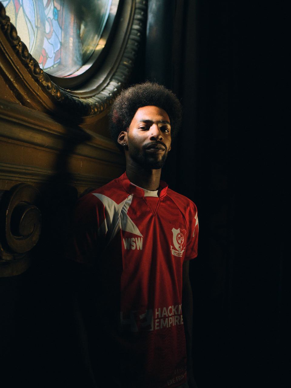 Hackney Women's FC player in the red Hackney Empire jersey inside Hackney Empire