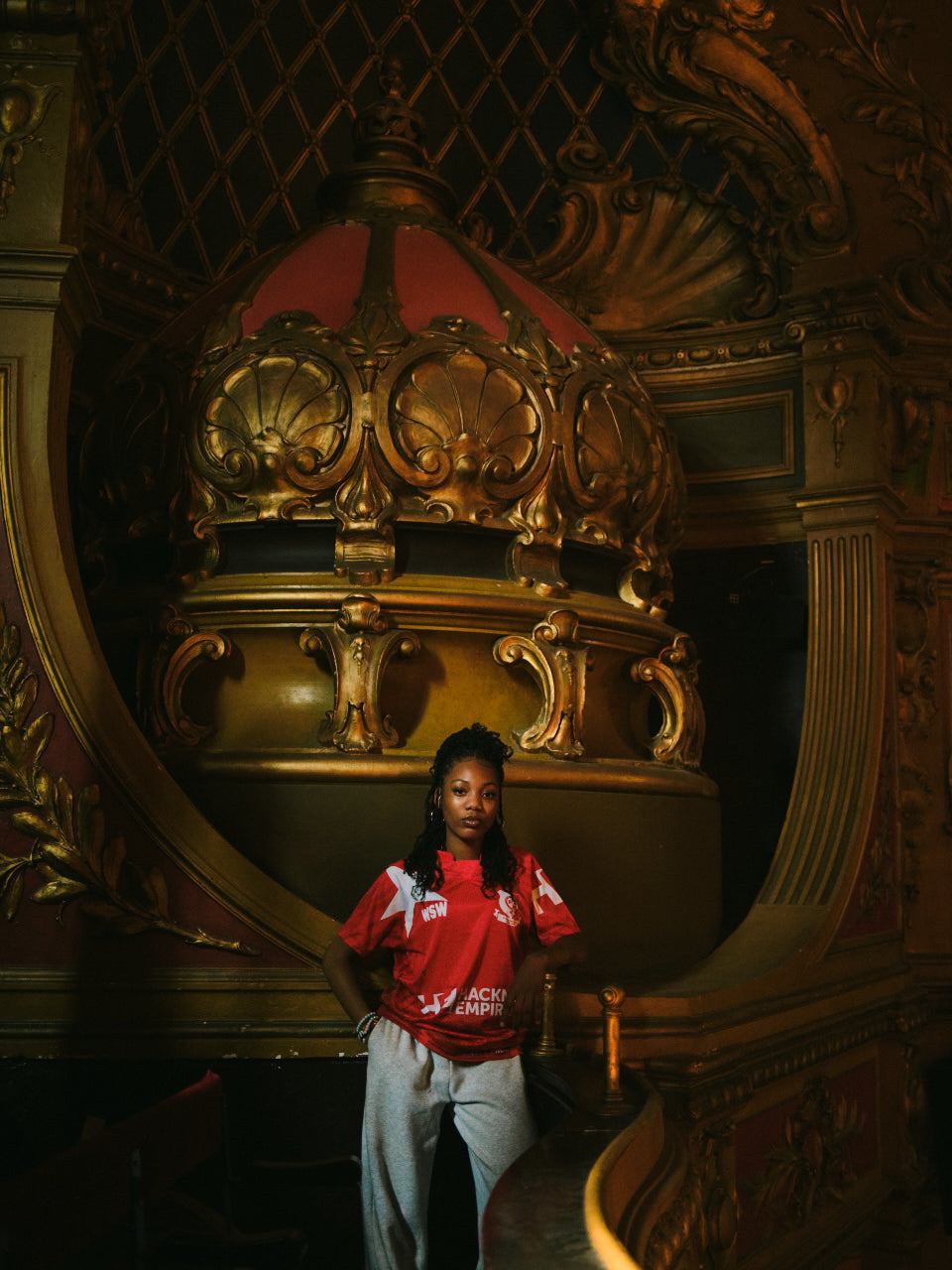 Hackney Women's FC player in the red Hackney Empire jersey inside a Hackney Empire theatre box